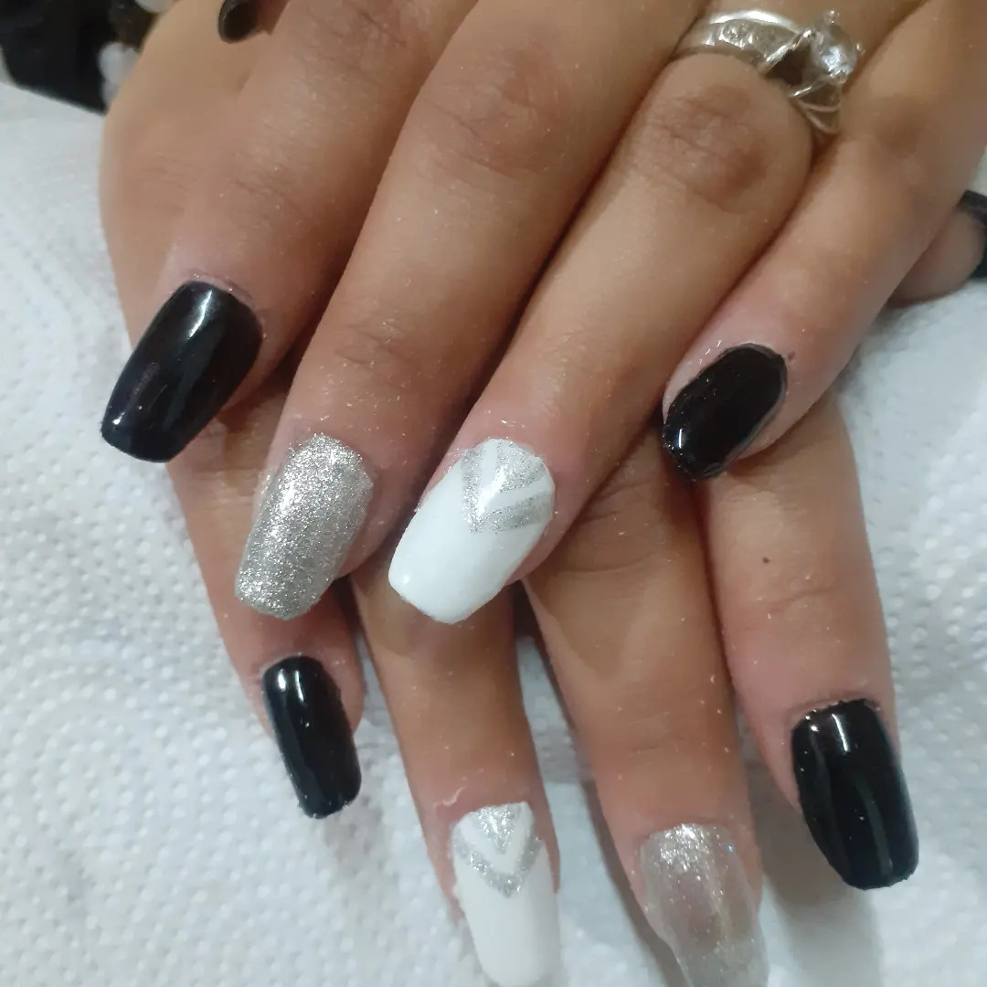 Uñas en negro, glitter plateado y blanco con V plateadas